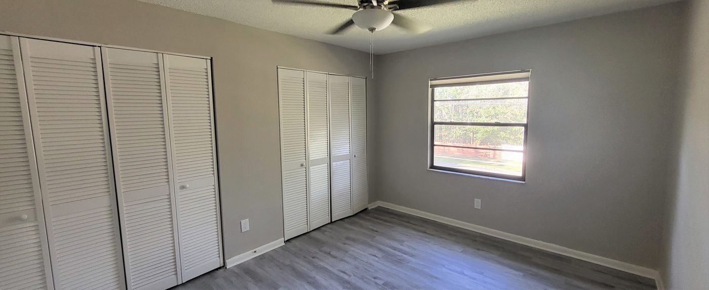 Bedroom with gray plank floors, a ceiling fan and louvered closet doors at Hyde Park