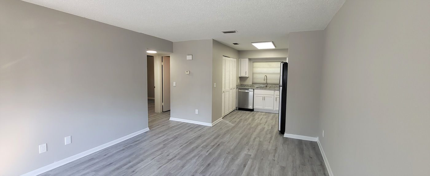 Living room with gray plank floors looking toward the kitchen at Hyde Park