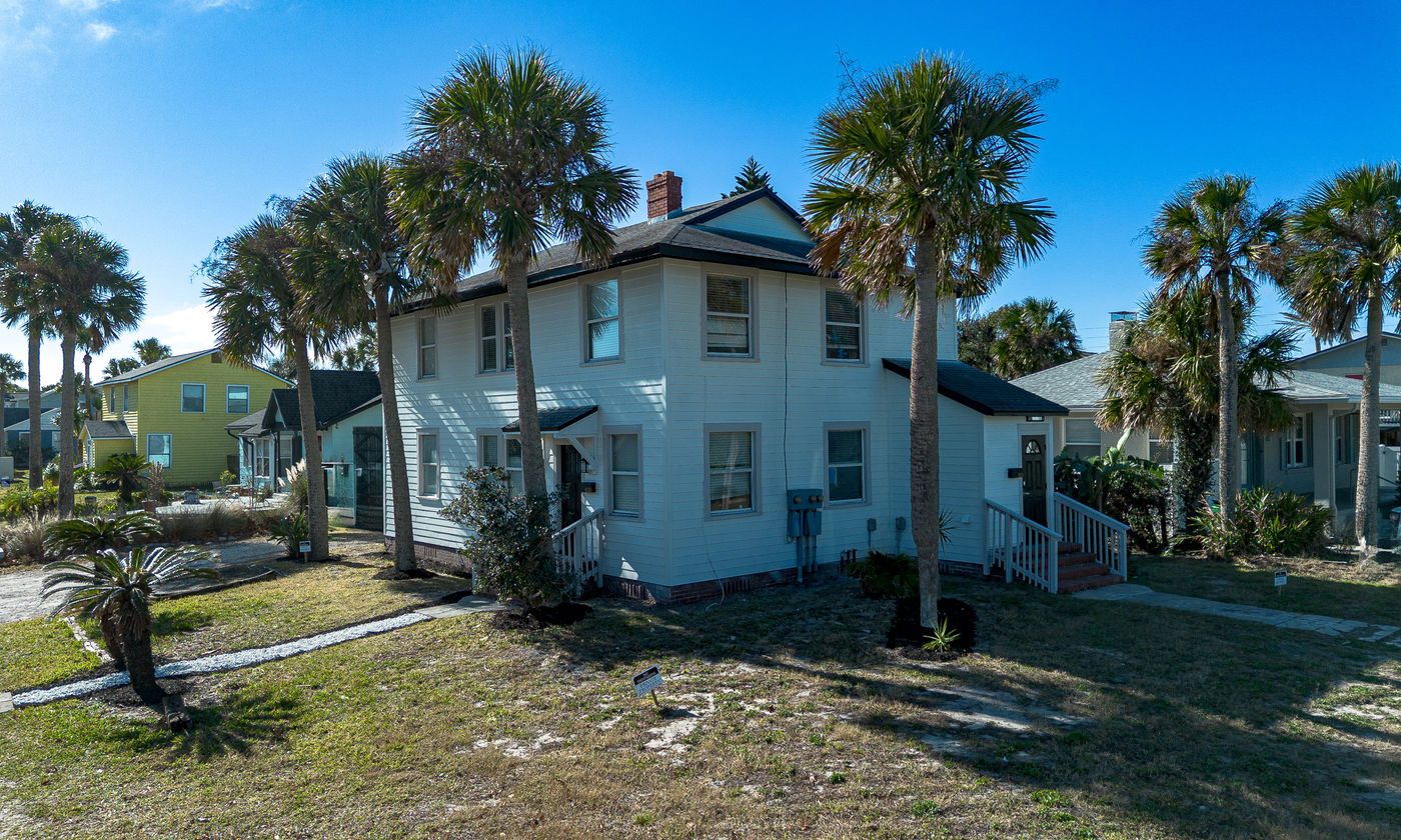 White two-story building among palms at Neptune Beach